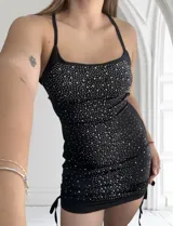 Minivestido negro ajustado al cuerpo, con escote recto y breteles finos. Decorado con strass plateados.