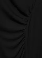 Vestido largo negro de diseño entallado, con escote asimétrico tipo off-shoulder y manga larga. Presenta detalles fruncidos laterales que realzan la silueta.