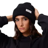 Gorro de lana tejido con diseño acanalado y vuelta en el borde. Incluye una etiqueta rectangular con el logo de la marca Rusty en la parte frontal.