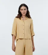 Camisa de viscosa color mostaza, de manga corta, con cuello camisero y cierre frontal con botones.