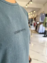 Remera de corte oversize color azul, con efecto gastado y pequeño texto bordado en el pecho.