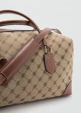 Bolso tipo bowling de diseño estructurado, confeccionado en tejido con estampado de monograma en tonos beige y marrón. Presenta detalles en cuero sintético marrón en las asas, esquinas y parches de sujeción, con herrajes metálicos dorados.