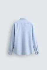 Camisa de manga larga, color celeste con finas rayas verticales blancas, cuello italiano y cierre frontal de botones.