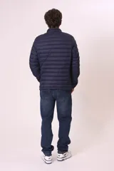 Chaqueta acolchada tipo puffer, color azul marino, con cuello alto y cierre frontal de cremallera.