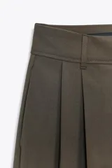 Pantalón de tiro medio con pinzas en el delantero, corte recto y amplio. Cuenta con trabillas en la cintura, bolsillos laterales y cierre frontal con cremallera, botón y gancho metálico.