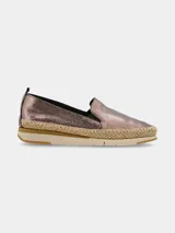 Zapatilla slip on de mujer, color cobre metalizado con efecto craquelado. Presenta una plataforma con suela de goma y una banda de yute trenzado alrededor de la base, estilo alpargata.