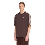 Remera de algodón con corte oversized, color marrón, con cuello redondo, logo del trébol bordado en el pecho y las icónicas tres tiras de la marca en color claro sobre los hombros y mangas.