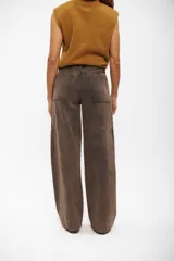 Pantalón tipo jean de corte cargo, color marrón con efecto lavado. Presenta costuras verticales decorativas, bolsillos laterales y diseño de pierna ancha.