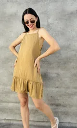 Vestido corto color mostaza, con escote halter y falda con volantes.