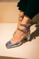 Zapato de tacón plateado con glitter, punta cuadrada, doble tira con hebilla al tobillo y forro rosa.