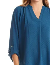 Blusa de color blanco con escote en V y cuello mao. Presenta mangas largas con presilla y botón para regular el largo, y un corte holgado con ruedo redondeado.