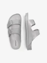 Sandalias planas de diseño ergonómico con doble tira ajustable con hebillas, confeccionadas en material EVA con acabado brillante plateado.