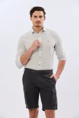 Bermuda cargo color azul marino, de gabardina con bolsillos laterales con solapa en las piernas y presillas para cinturón. Incluye cinturón de lona trenzada oscura con detalles en cuero sintético y hebilla metálica.