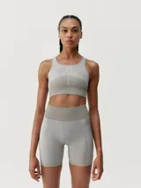 Top deportivo color gris con líneas decorativas blancas, de sujeción alta y copas extraíbles.