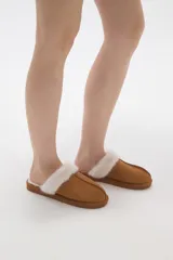 Pantuflas cerradas color marrón con ribetes de piel sintética en la abertura y suela plana.