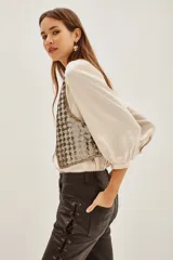 Chaleco corto con diseño de lentejuelas brillantes en tono dorado y plateado. Presenta un corte clásico con bordes definidos y forro interior suave.