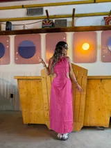 Vestido largo fucsia con espalda descubierta y aberturas laterales en la cintura.