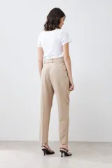 Pantalón de vestir color beige, de corte recto, con pinzas, bolsillos laterales y cinturón con hebilla forrada.