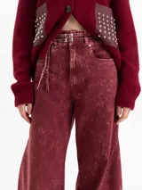 Pantalon wide leg de tiro medio confeccionado en denim con lavado efecto gastado. Presenta pierna amplia, cinco bolsillos, cierre frontal con botón y cinturón integrado del mismo tejido con doble hebilla metálica.