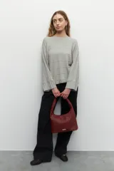 Cartera tipo hobo color borgoña, confeccionada en símil cuero trenzado, con asa fija anudada y tres bolsillos internos.