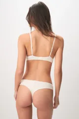 Bombacha colaless color beige de tejido acanalado con detalles de encaje en los laterales.