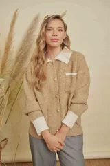 Saco de punto texturizado en color beige, con diseño de cuello redondo, cierre frontal y detalles en contraste de color blanco en los puños y en un bolsillo frontal.
