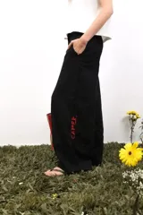 Pantalón de lino blanco de corte amplio y tiro medio-bajo. Presenta bolsillos laterales y traseros, cierre con botón metálico grabado y detalles de bordados laterales y traseros.