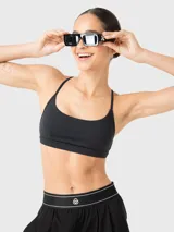 Top deportivo de bajo impacto, color negro, con escote redondo y tirantes finos ajustables que se cruzan en la espalda. Incluye almohadillas removibles.