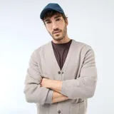 Cárdigan de punto color beige con cuello en V, cierre frontal con botones y dos bolsillos delanteros. Presenta puños y ruedo acanalados.