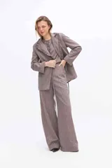 Pantalón de pierna amplia y tiro alto, confeccionado en tejido a rayas con una mezcla de algodón, poliéster y lino. Presenta un diseño de corte sastrero con bolsillos laterales y trabillas para cinturón.