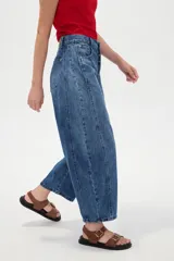 Pantalón de jean blanco de tiro medio, con diseño de silueta barrel, bolsillos clásicos y costuras con pinzas decorativas en la zona de las rodillas.