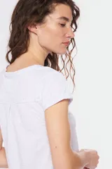 Remera color beige con cuello redondo, mangas cortas, bolsillo pequeño en el pecho y media botonadura frontal.