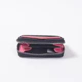 Monedero color negro con textura trenzada, cierre perimetral de cremallera y bolsillo exterior portatarjetas.