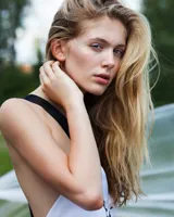 Vestido corto blanco de gasa y seda fina, con escote pronunciado y apliques de perlas de vidrio. Espalda abierta con tirantes cruzados anchos y caída asimétrica.