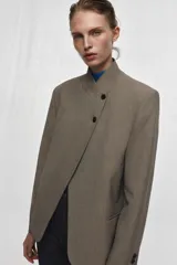 Blazer de cuello subido con cierre frontal cruzado de botones. Presenta manga larga con hombreras y puños con botones, bolsillos de vivo en el delantero y forro interior.