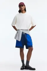 Short de baño y deportivo confeccionado en nylon, de corte holgado. Presenta un diseño de bloques de color en tonos azul, azul marino y blanco. Cuenta con cintura elástica con cordón ajustable blanco, bolsillos laterales y aberturas en los costados del ruedo. Incluye suspensor interno de malla.