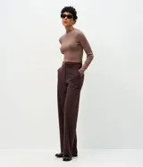 Suéter de punto canelado color beige, con cuello alto y manga larga. Presenta un diseño ajustado al cuerpo, confeccionado en una mezcla de viscosa, poliéster y poliamida.