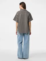 Camisa de popelina con mangas cortas, cuello clásico y cierre frontal de botones. Presenta un estampado de rayas verticales finas en tonos marrón oscuro y blanco.