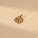 Dije circular de San Benito con diseño grabado en relieve, fabricado en una combinación de plata y oro.