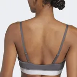 Bralette deportivo Adidas Hyperglam color gris oscuro con tirantes finos ajustables. Presenta detalles de costuras curvas y una banda elástica inferior en color blanco con el logo de Adidas.