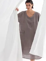 Vestido midi color visón, de lino, con cuello en V, mangas cortas y dos bolsillos frontales.