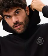 Campera deportiva Get Over confeccionada en mezcla de poliéster, viscosa y elastano, de color negro con capucha fija, cierre frontal y bolsillos laterales. Cuenta con un pequeño estampado circular con lettering en el pecho.
