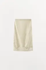 Falda midi de tiro medio color beige en tejido de viscosa con estampado jacquard y aplicación de encaje a tono en el bajo, con cierre lateral de cremallera oculta.