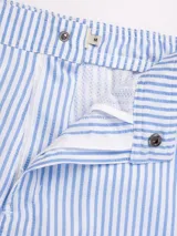 Short de baño celeste con rayas verticales blancas y parche bordado en la pierna derecha.