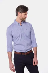 Camisa de manga larga con cuello abotonado y estampa a cuadros en tonos de azul y blanco. Presenta un bolsillo aplicado en el pecho con detalle de bordado y cierre frontal con botones.