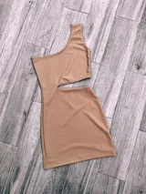 Vestido corto color beige, con un solo hombro y abertura en la cintura.