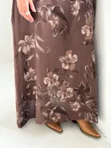Vestido largo marrón de lino con estampado floral, cuello redondo holgado y mangas tres cuartos.