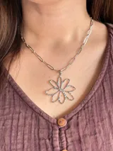 Collar de acero quirúrgico con cadena de eslabones rectangulares y un gran dije colgante en forma de flor con textura martillada.