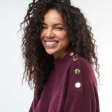 Vestido corto tipo sweater de punto color bordó, con cuello redondo, mangas largas con puños ajustados y detalle de botones decorativos en el hombro.