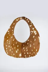 Cartera de silueta ovalada con asa circular integrada, confeccionada en cuero con estampado animal print tipo ciervo en tonos marrón y blanco.
